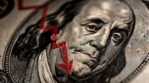 Close-up of Benjamin Franklin on a dollar bill with a red downward arrow illustrating why are all markets crashing