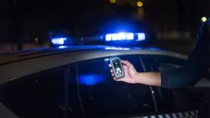 Police officer uses a breathalyzer device during a traffic stop, illustrating drunk-driving detection in practice