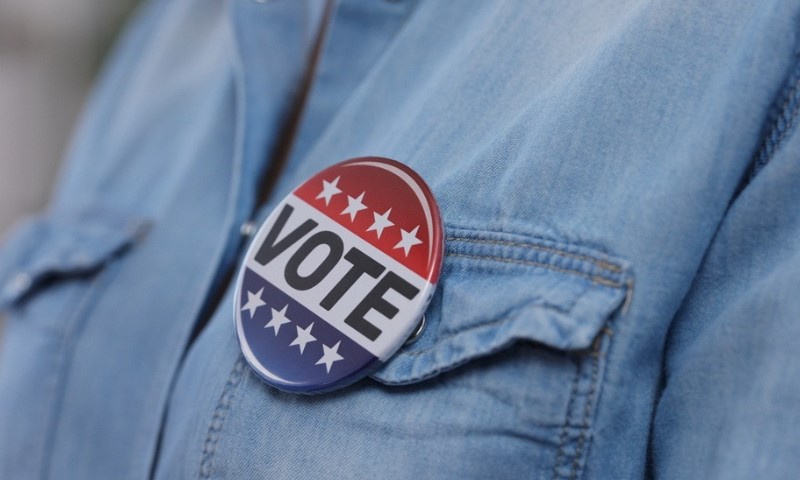 Close-up of a button reading "Vote" pinned to a denim shirt