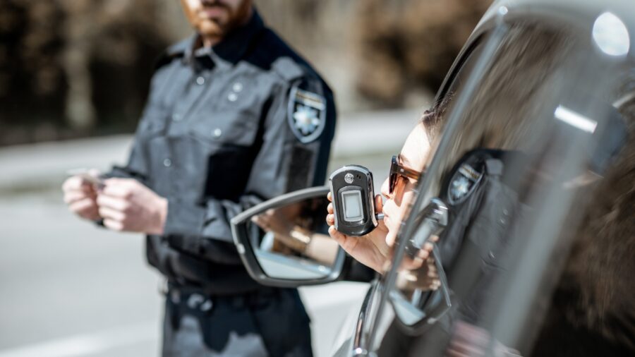 Driver uses a handheld breathalyzer during a roadside stop as part of drunk-driving detection procedures
