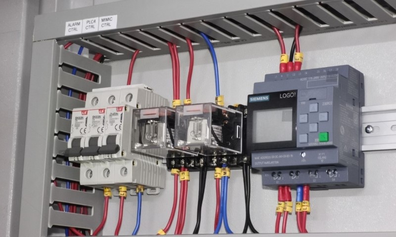Electrical control panel featuring colorful wires, switches, and a digital control unit