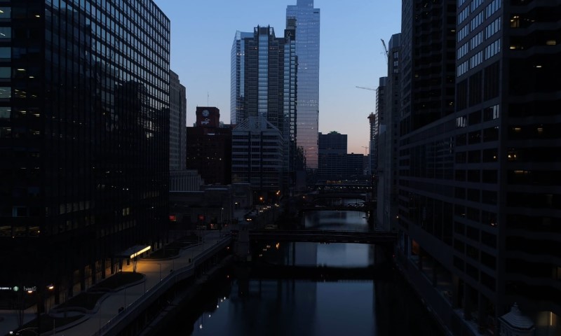 Chicago city skyline at dusk with towering skyscrapers and a calm river reflecting the fading light