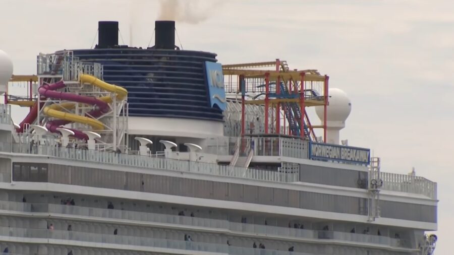 Top deck of a cruise ship with water slides and passengers visible on balconies