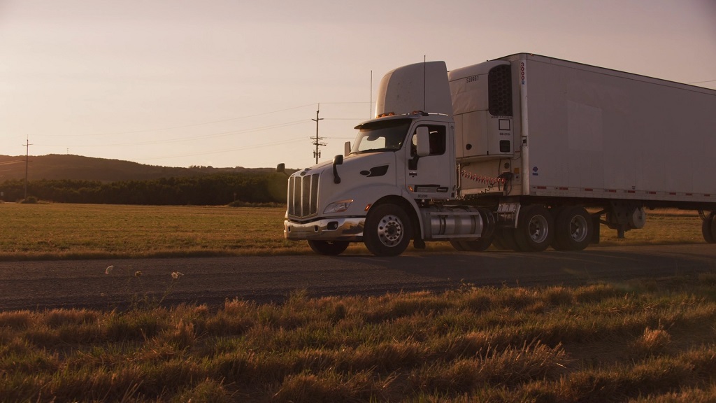 White Super Ego semi truck driving on rural road at sunset during freight transport