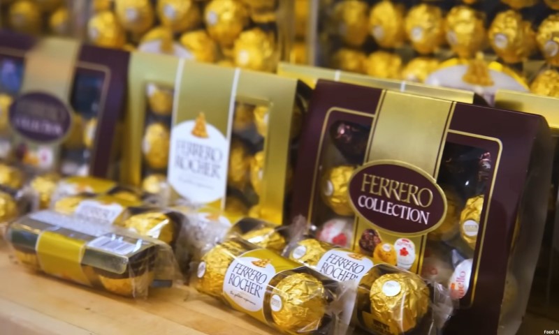 Assortment of Ferrero Rocher chocolates in gold wrappers and brown boxes displayed on a shelf