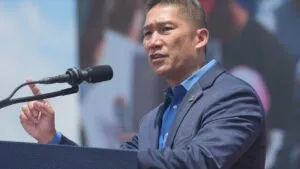 Hung Cao speaks at a podium with a microphone, gesturing during a public address