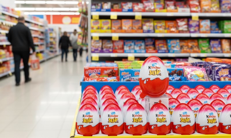 Rows of Kinder Joy eggs are neatly displayed in a colorful supermarket aisle