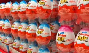 Rows of colorful Kinder Joy eggs are stacked on a store shelf