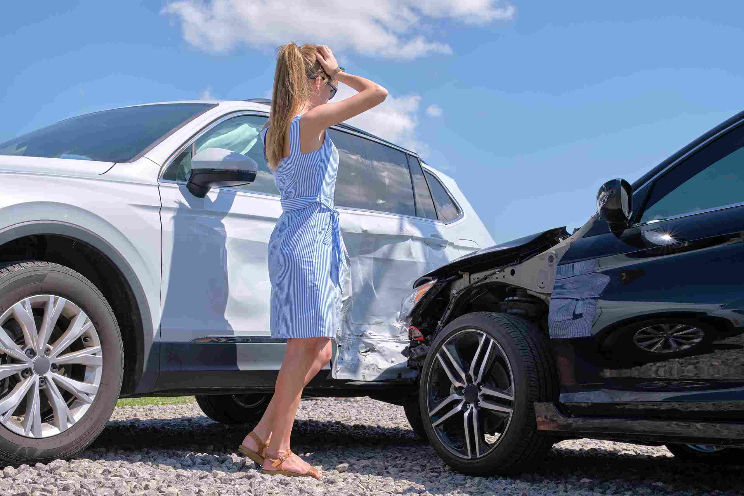 Woman standing beside a damaged SUV after a car accident