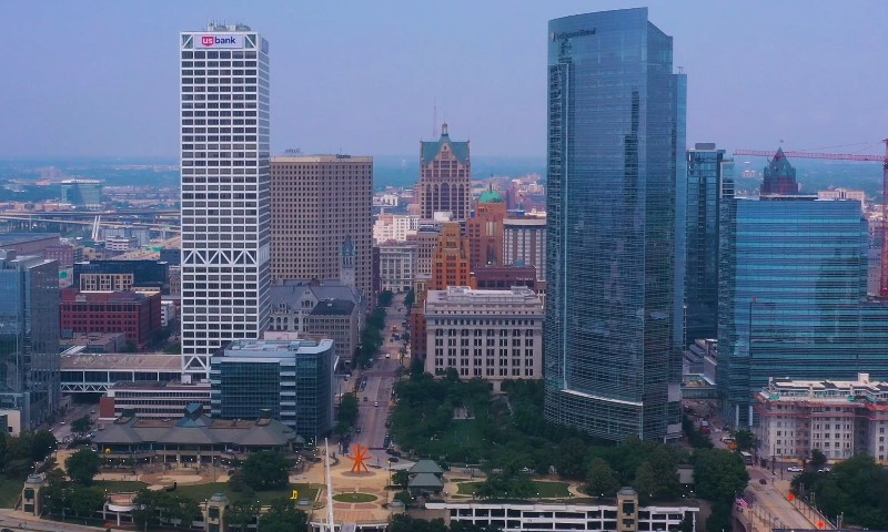 Aerial view of downtown Milwaukee with tall skyscrapers, including glass and brick buildings