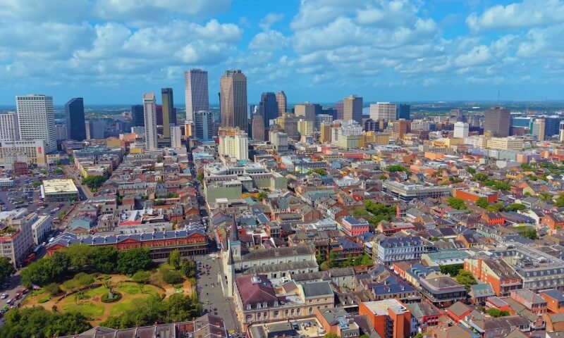 Aerial view of a vibrant cityscape featuring a mix of historic and modern buildings under a bright blue sky with fluffy clouds