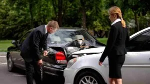Man and woman examining rear end damage between two cars after an accident with Mini-Tort System Rule