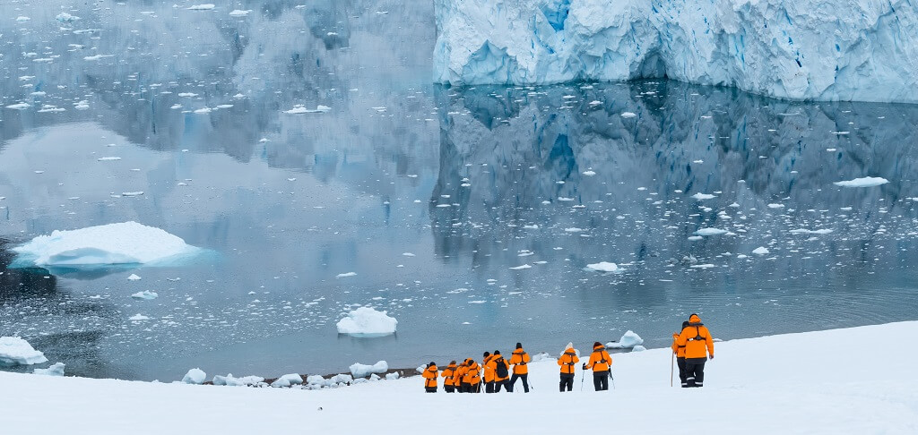Antarctica tourism group walking across snowy coastline during guided expedition landing