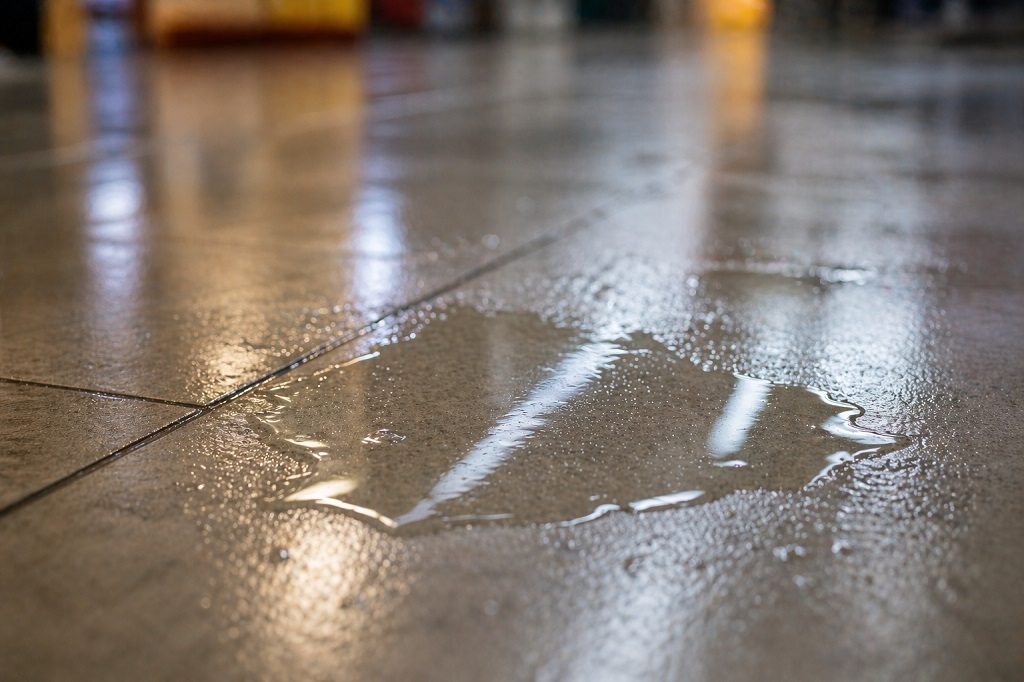 Close-up of wet supermarket floor with visible puddle and light reflection