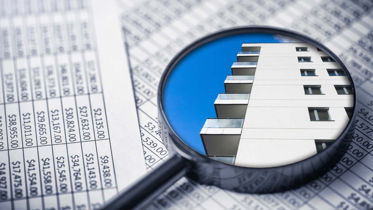 Real estate market data reviewed with a magnifying glass over an apartment building