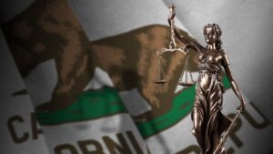Lady Justice statue in front of a blurred California flag