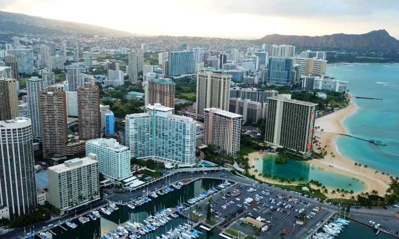 Aerial view of a cityscape with tall buildings lining a tranquil beach