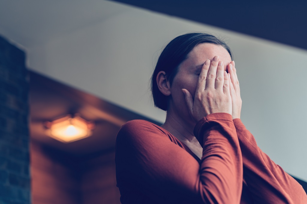 Woman covering her face with both hands, showing the emotional weight of trauma and silence