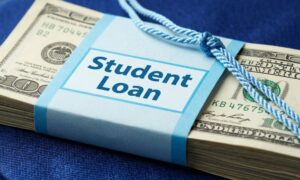 A stack of US dollar bills is bundled with a light blue band that says "Student Loan."