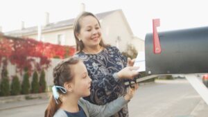 A woman and child place election mail into a residential mailbox