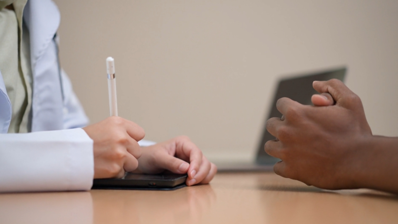 A clinician takes notes during a behavioral health consultation with a patient.