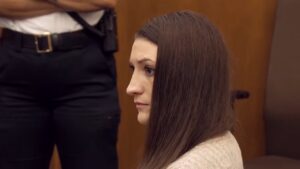 Lindsay Clancy sits in a courtroom beside a court officer