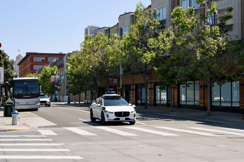 Waymo robotaxi driving through an urban intersection