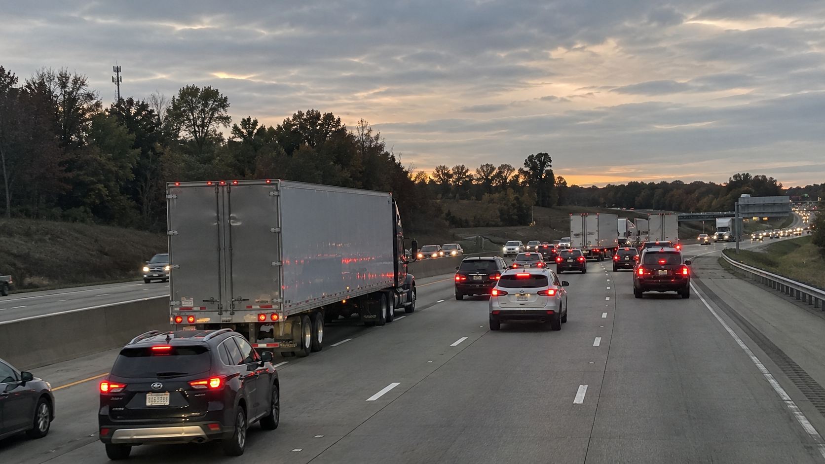 Semi-truck traveling among cars on a congested highway.