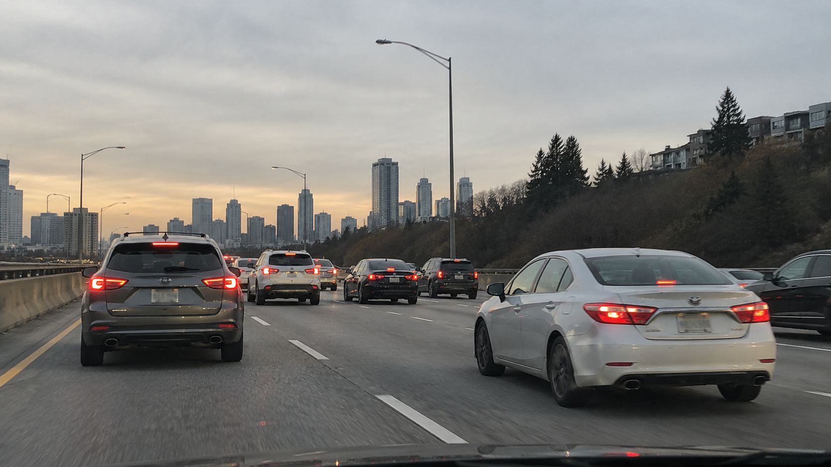 Cars traveling on a multi-lane highway near a city.