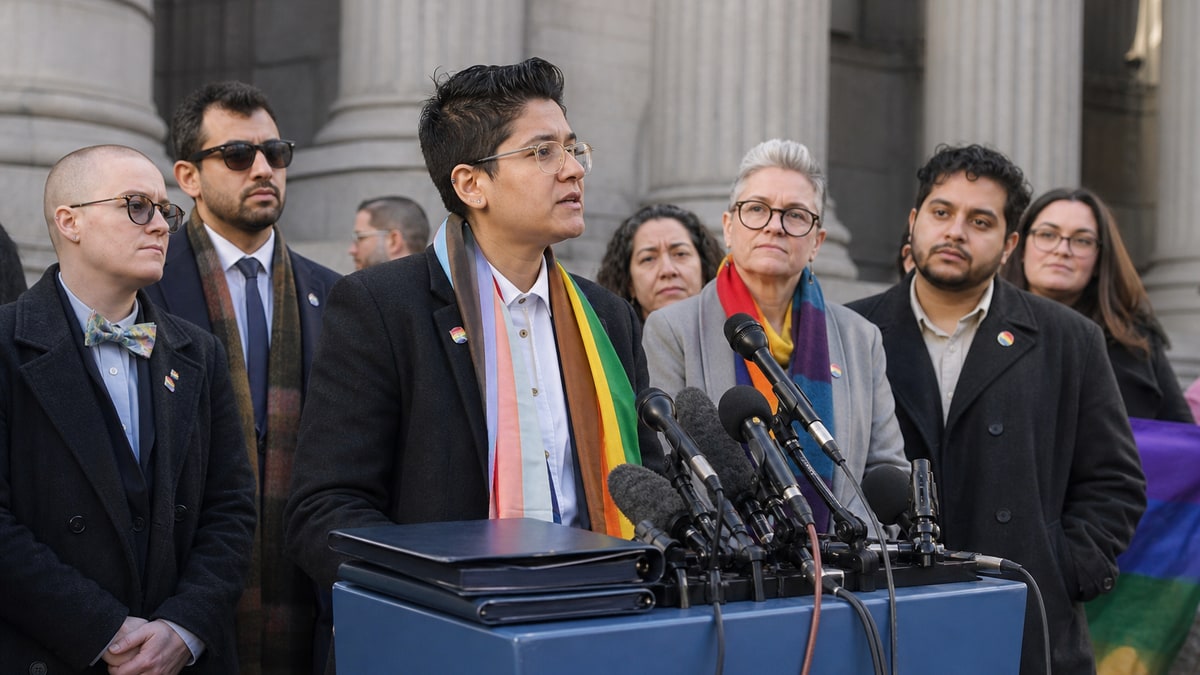 A blue lectern with microphones stands before advocates outside a civic building