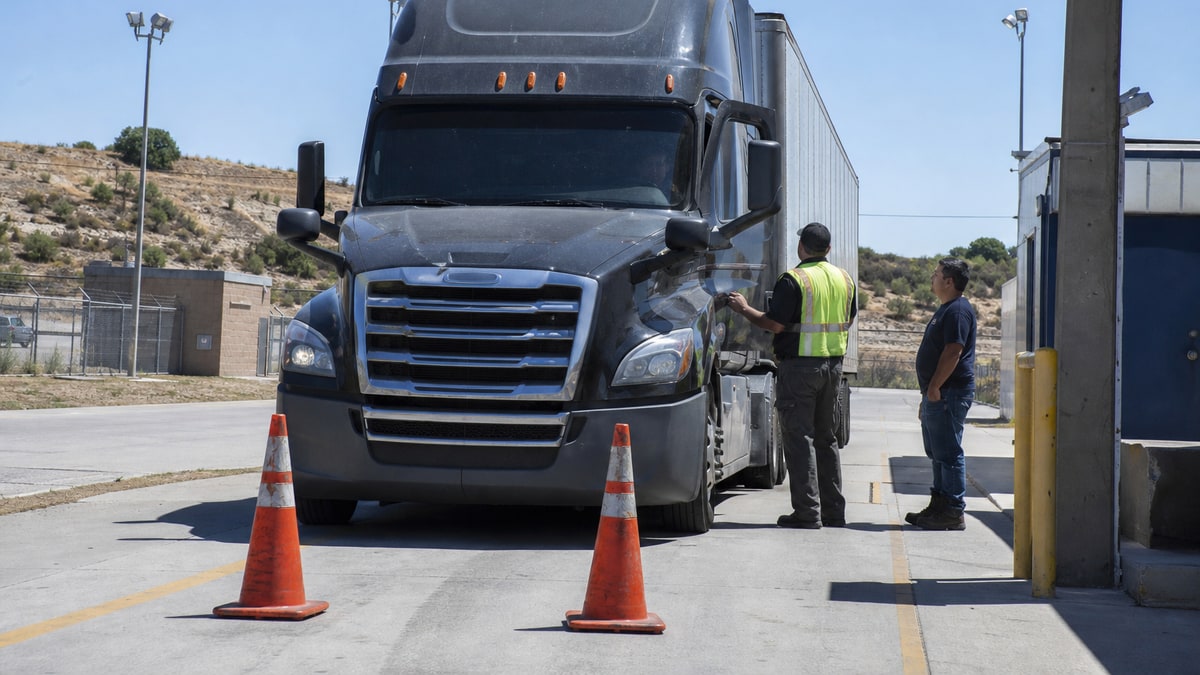 Commercial truck stopped between cones as an officer stands by the driver-side door