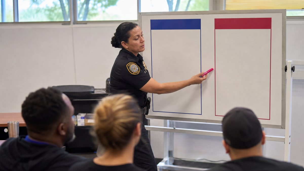 Instructor moves a color marker on a blank policy board in a training room