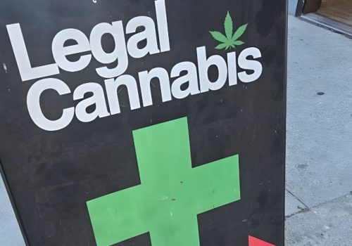 Black A-frame sign advertising "Legal Cannabis" with white lettering and a green marijuana leaf icon