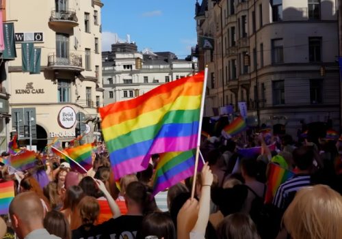 A vibrant Pride parade fills the city streets