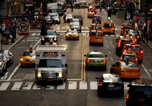 A bustling city street filled with numerous cars and taxis navigating through traffic