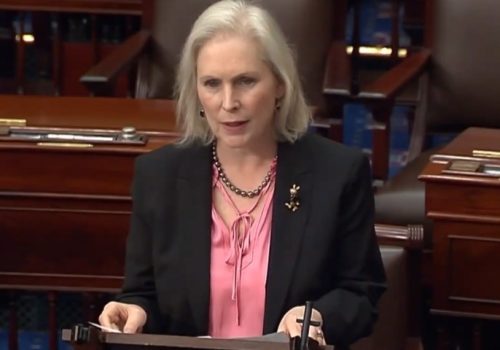 Senator Gillibrand in a suit speaks confidently at a desk