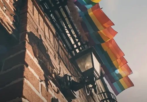 Colorful Pride flags flutter against a brick building