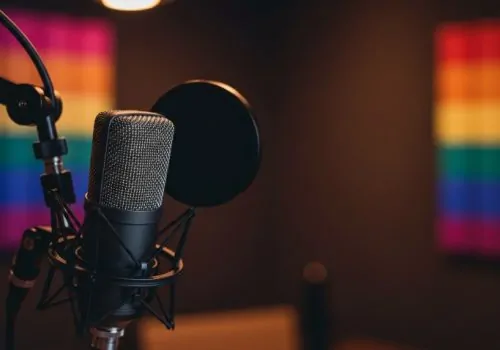 Studio microphone against a blurred backdrop of a rainbow flag