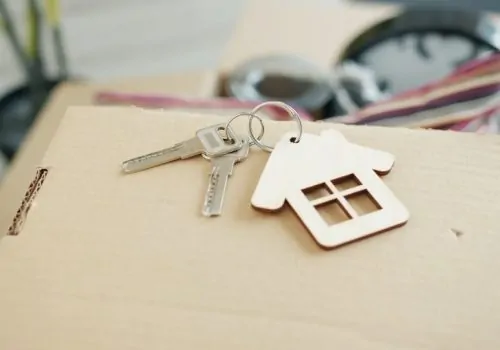 Keys and a house-shaped charm rest on a cardboard box