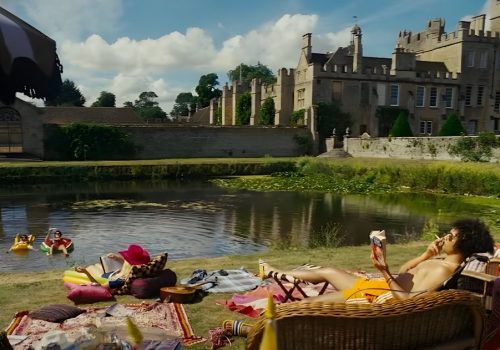 A scene from the Saltburn movie, picnic by the lake, featuring colorful textiles and comfortable seating