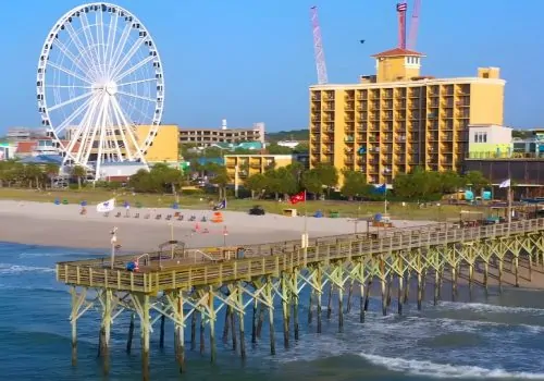 Sunny beachfront scene with a vibrant Ferris wheel and a charming pier