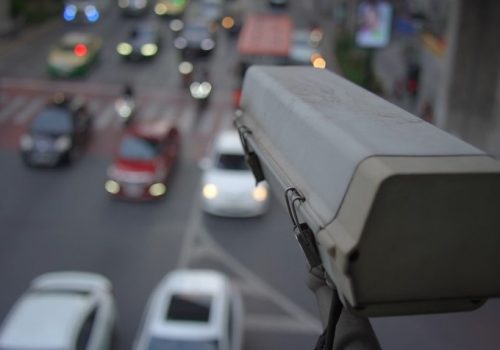 Surveillance camera overlooks a bustling street with blurred traffic lights and cars