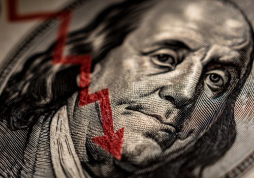 Close-up of Benjamin Franklin on a dollar bill with a red downward arrow illustrating why are all markets crashing